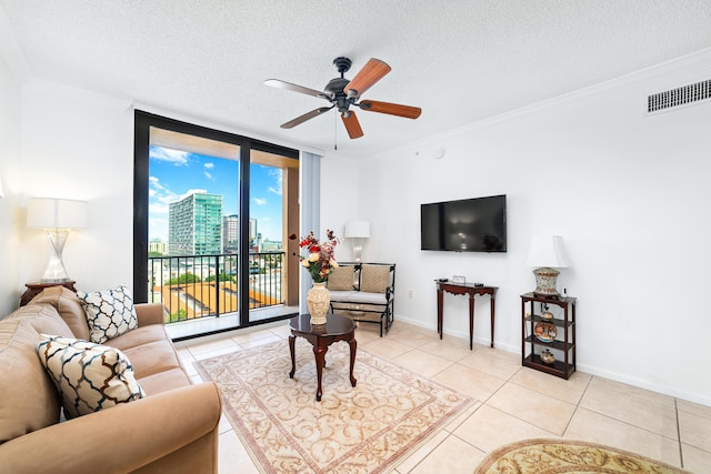 living room featuring a textured ceiling, light tile patterned flooring, visible vents, ornamental molding, and floor to ceiling windows