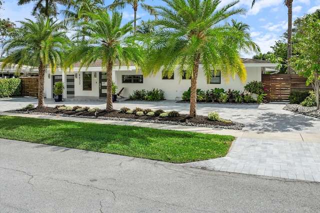 view of front of house with fence, decorative driveway, and stucco siding