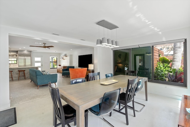 dining space featuring concrete flooring, visible vents, and a ceiling fan