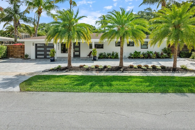 view of front of property featuring a garage, fence, decorative driveway, and stucco siding