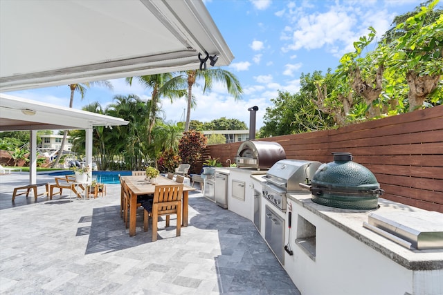 view of patio featuring a fenced in pool, area for grilling, a fenced backyard, exterior kitchen, and outdoor dining space