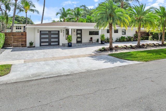 view of front of property featuring an attached garage, fence, and decorative driveway