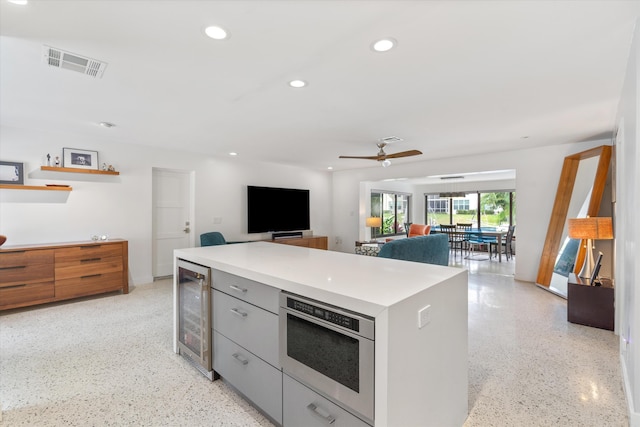 kitchen featuring visible vents, wine cooler, a center island, light speckled floor, and recessed lighting