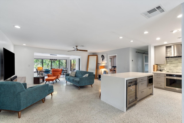 kitchen featuring a barn door, visible vents, wall chimney exhaust hood, wine cooler, and oven