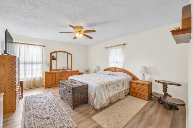 bedroom featuring a textured ceiling, light wood finished floors, and a ceiling fan