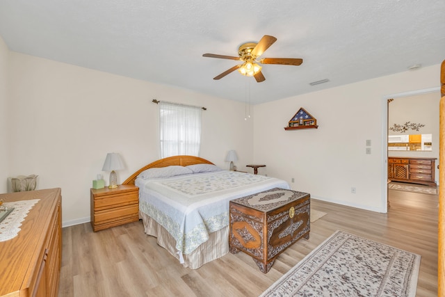 bedroom featuring light wood finished floors, baseboards, visible vents, and ceiling fan