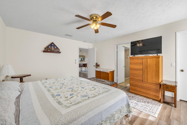 bedroom featuring visible vents, ceiling fan, light wood-style flooring, and a textured ceiling