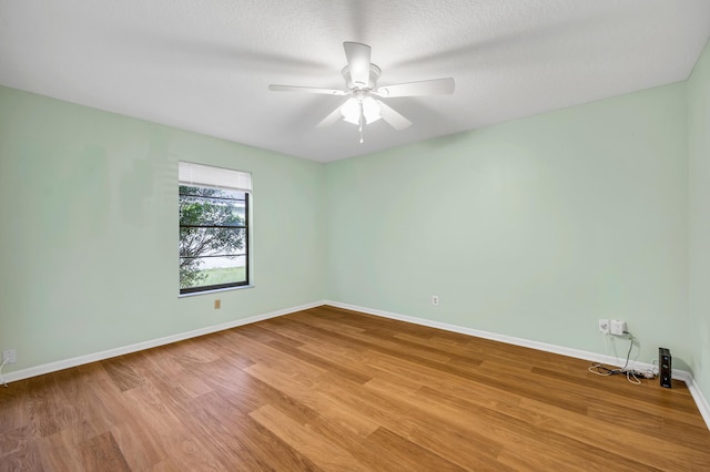 unfurnished room with a textured ceiling, wood finished floors, a ceiling fan, and baseboards