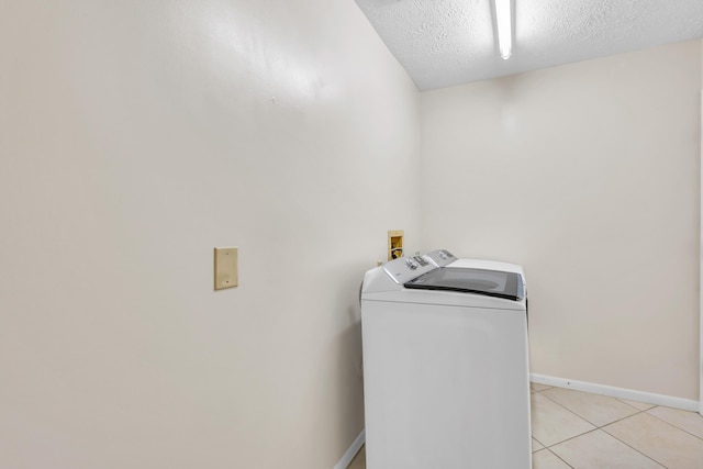 clothes washing area with washer / dryer, laundry area, baseboards, a textured ceiling, and light tile patterned flooring