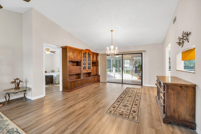 living room featuring light wood-type flooring, high vaulted ceiling, baseboards, and ceiling fan with notable chandelier