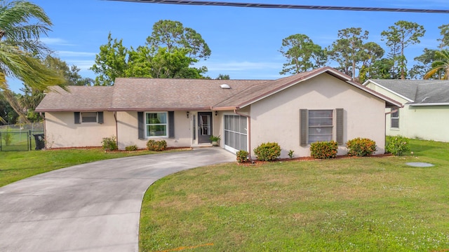 ranch-style house with driveway, fence, a front lawn, and stucco siding