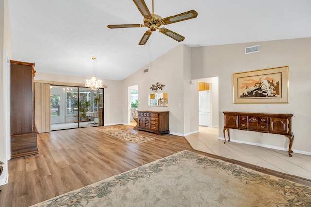 interior space featuring baseboards, visible vents, wood finished floors, high vaulted ceiling, and ceiling fan with notable chandelier