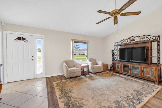 living room featuring lofted ceiling, light wood-style floors, ceiling fan, and baseboards