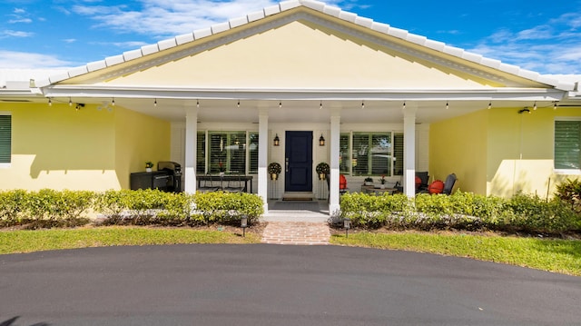 view of front of home with stucco siding, covered porch, and a tiled roof