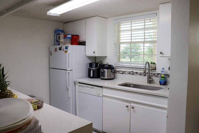 kitchen featuring white appliances, white cabinetry, light countertops, and a sink