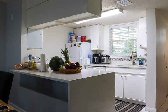 kitchen with white appliances, visible vents, a sink, white cabinets, and a textured ceiling