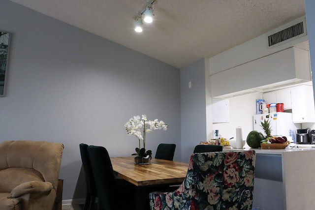 dining space with track lighting and visible vents