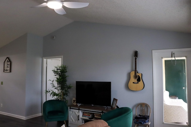 living area featuring a ceiling fan, baseboards, vaulted ceiling, dark wood-type flooring, and a textured ceiling