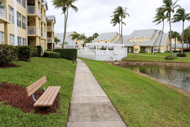 view of property's community with a residential view, a lawn, and a water view