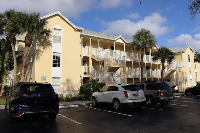 view of building exterior with stairway and uncovered parking