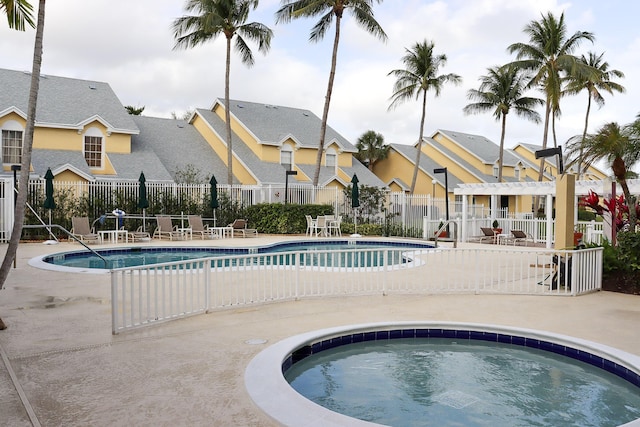 community pool featuring a community hot tub, a pergola, fence, a residential view, and a patio area