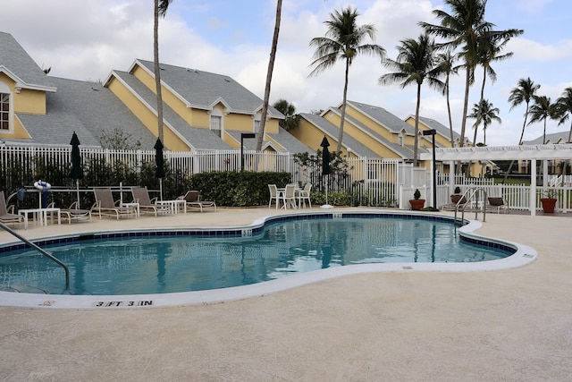 community pool with a patio area, a residential view, and fence