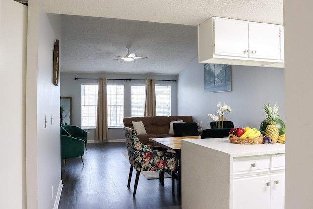 dining area featuring baseboards, a textured ceiling, a ceiling fan, and dark wood-style flooring