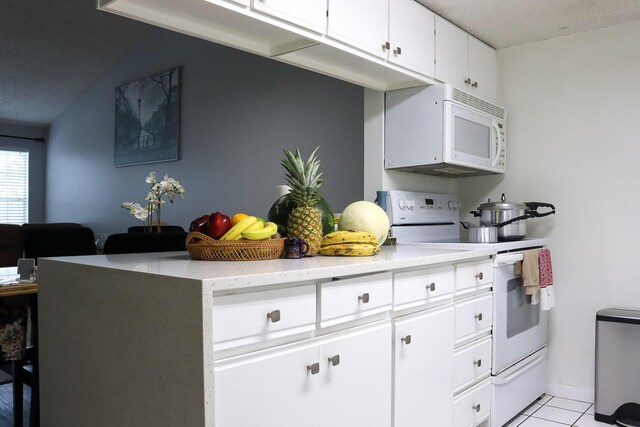 kitchen with light tile patterned floors, white cabinets, white appliances, and lofted ceiling