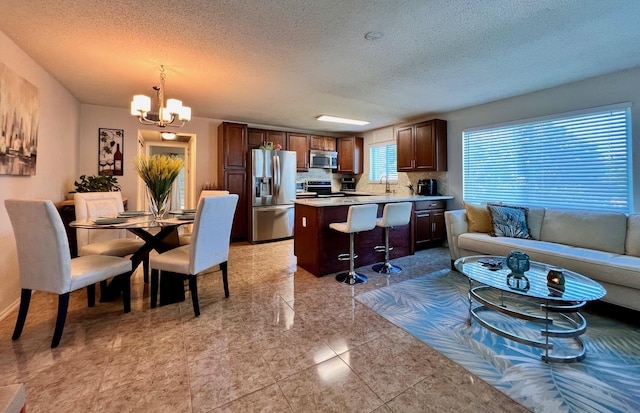 kitchen with a breakfast bar, an inviting chandelier, stainless steel appliances, light countertops, and pendant lighting