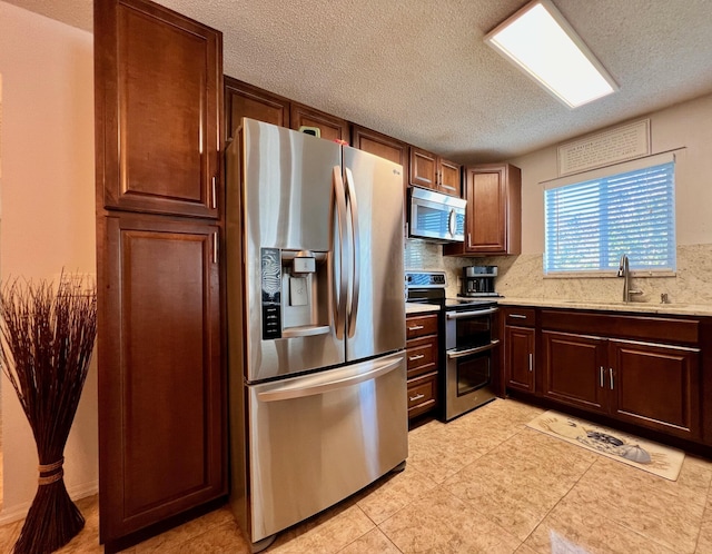 kitchen with stainless steel appliances, a sink, light countertops, and decorative backsplash