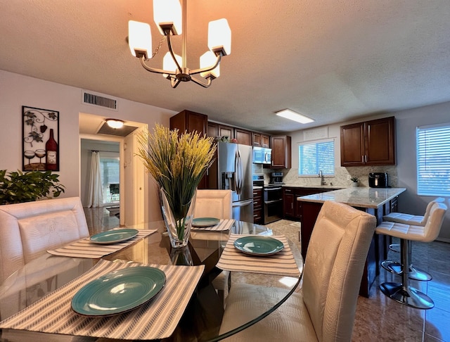 dining area featuring a textured ceiling, visible vents, and a notable chandelier