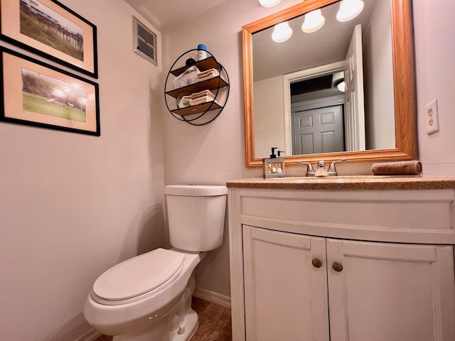 half bathroom featuring toilet, visible vents, vanity, and baseboards