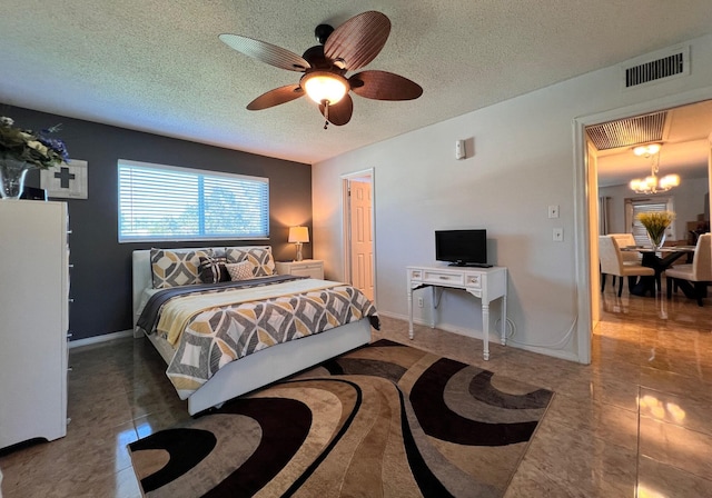 bedroom featuring baseboards, visible vents, a textured ceiling, and ceiling fan with notable chandelier