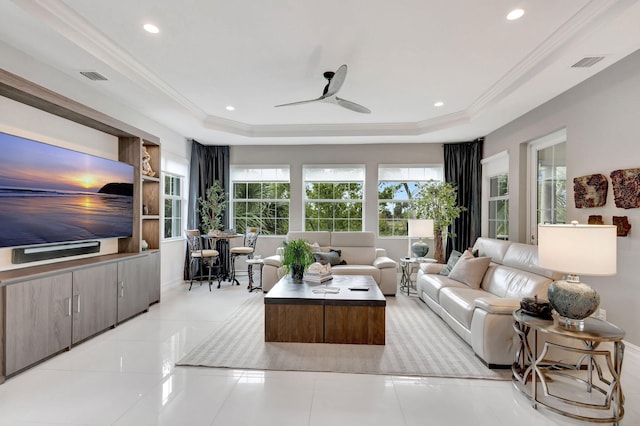 living room featuring a tray ceiling, light tile patterned flooring, visible vents, and crown molding