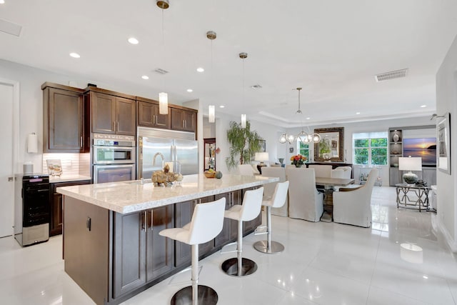 kitchen featuring appliances with stainless steel finishes, open floor plan, visible vents, and backsplash