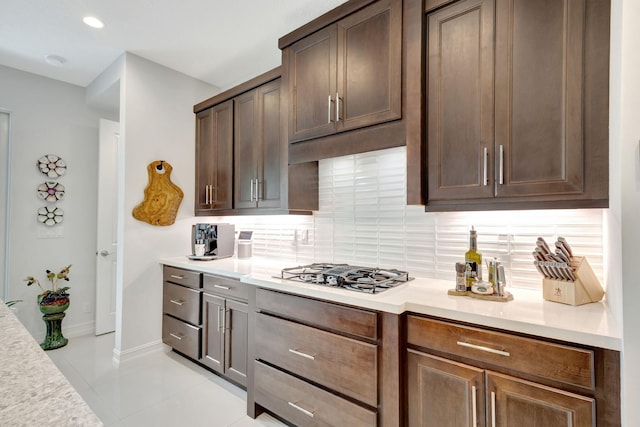 kitchen with light countertops, backsplash, gas cooktop, and baseboards