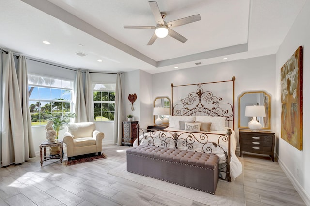 bedroom featuring baseboards, visible vents, a tray ceiling, and ceiling fan