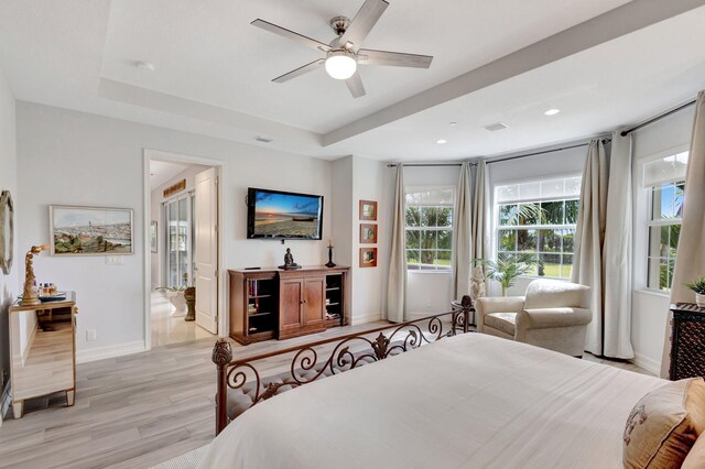 bedroom featuring baseboards, a tray ceiling, recessed lighting, and light wood-style floors