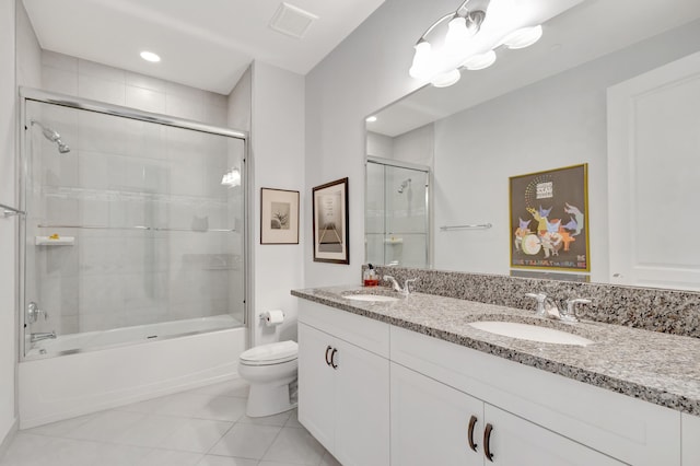 bathroom featuring toilet, tile patterned flooring, combined bath / shower with glass door, and a sink