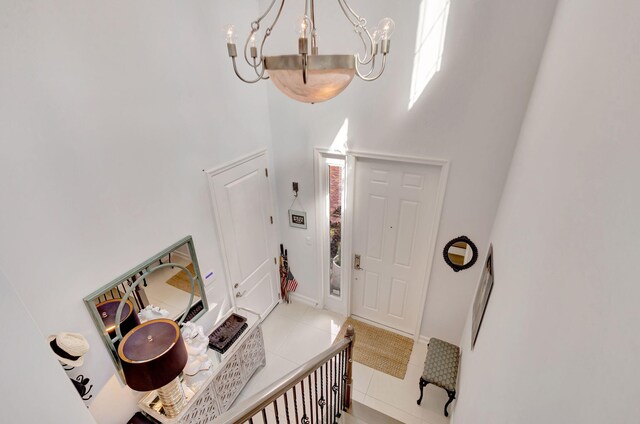 foyer featuring a chandelier, a high ceiling, light tile patterned floors, and baseboards