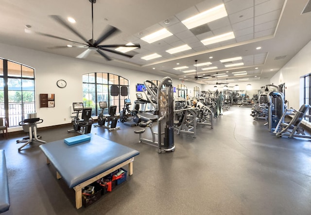 exercise room featuring a tray ceiling, visible vents, ceiling fan, a drop ceiling, and baseboards