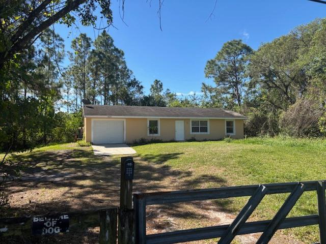 ranch-style home featuring a front yard, an attached garage, fence, and dirt driveway