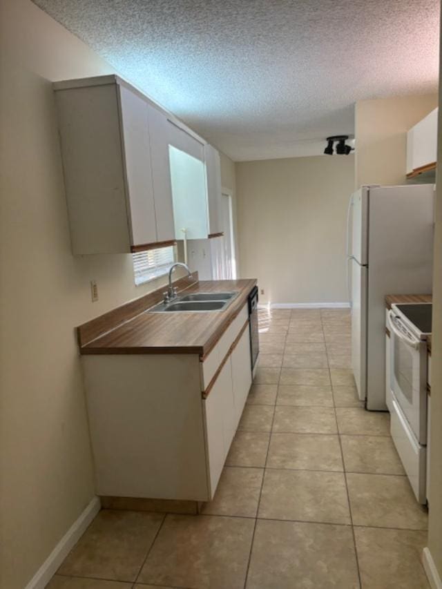 kitchen featuring light tile patterned floors, white appliances, a sink, and white cabinets