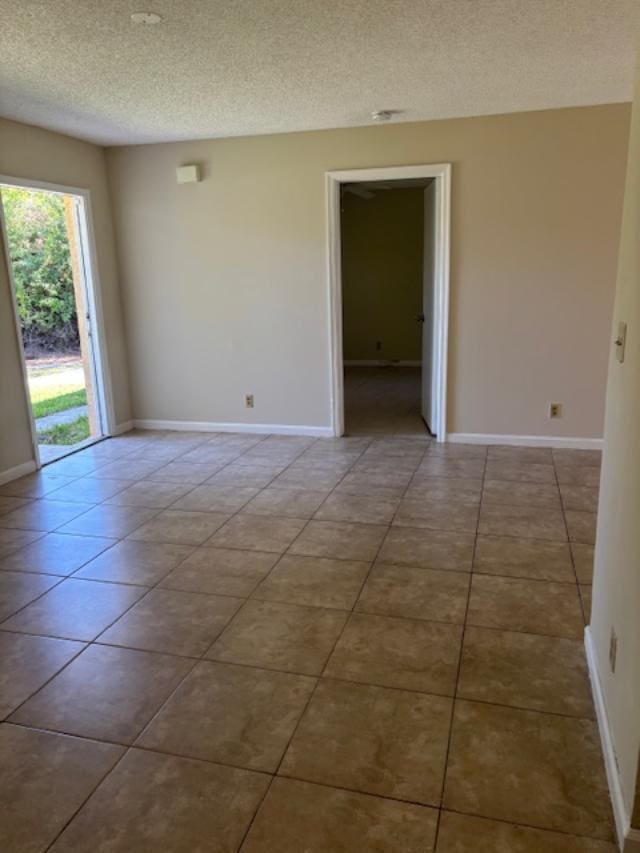 spare room featuring baseboards, a textured ceiling, and tile patterned floors