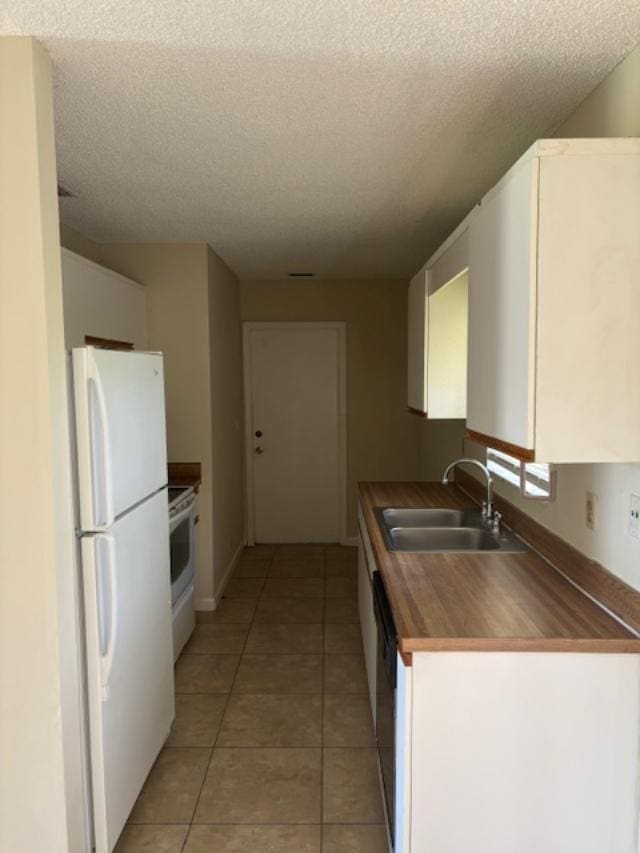 kitchen with electric stove, dark countertops, freestanding refrigerator, a sink, and dishwasher