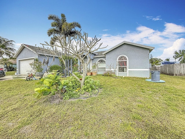 view of front of home with an attached garage, a front yard, fence, and stucco siding