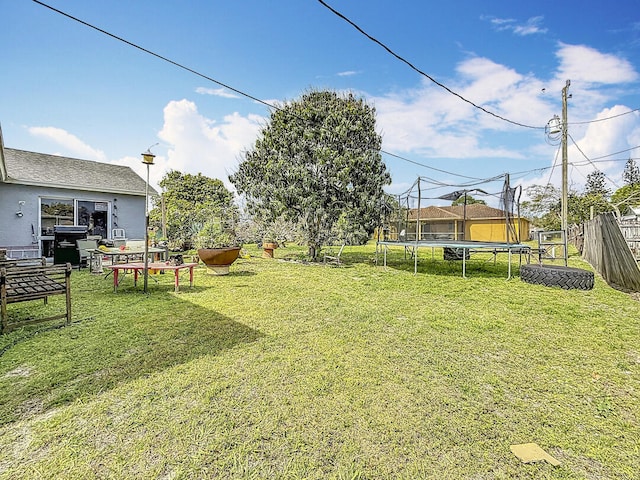 view of yard with a trampoline and fence