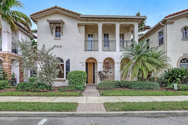 mediterranean / spanish home with a tiled roof, a balcony, and stucco siding