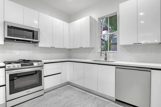 kitchen featuring stainless steel appliances, white cabinets, light countertops, and a sink