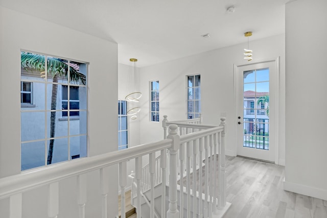 hallway with baseboards, wood finished floors, and an upstairs landing